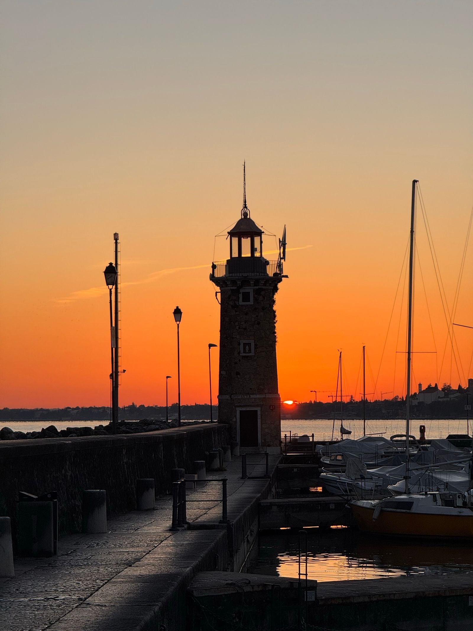 Il faro del porto di Desenzano del Garda al tramonto — da qui partono i pazienti di Trapianto Capelli Tirana